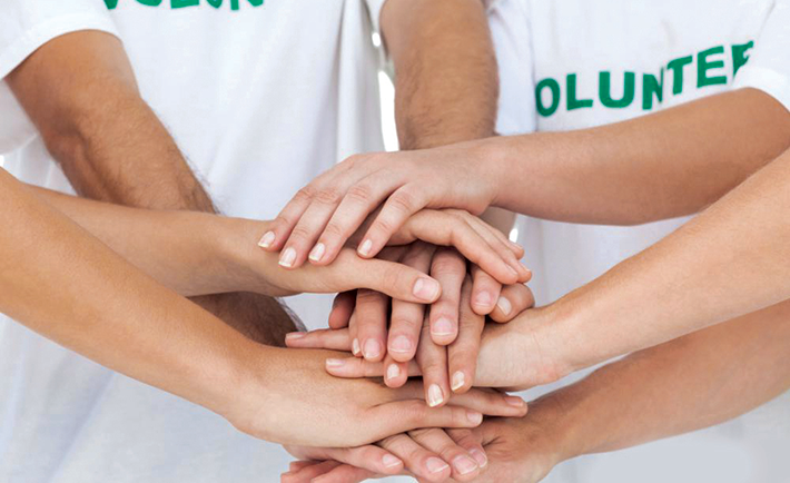 group-of-volunteers-in-white-shirts-with-hands-together