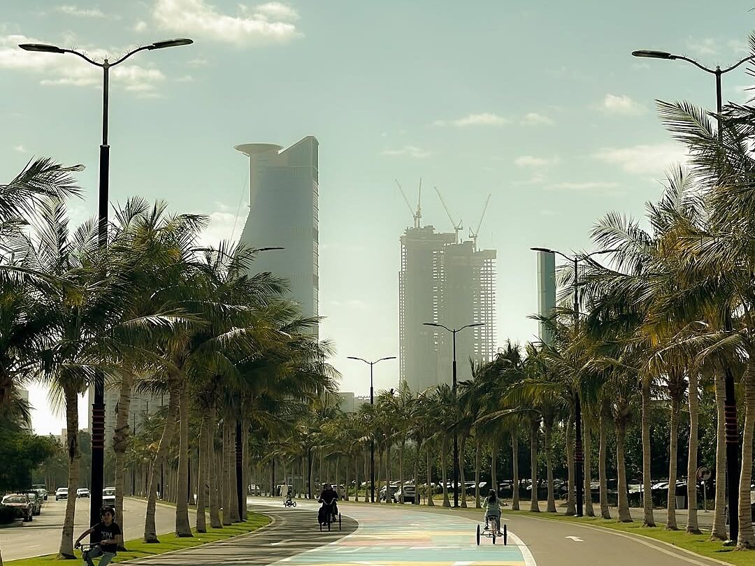Colorful Roshn Waterfront walkways in Jeddah lined with palm trees, stretching alongside the sea.